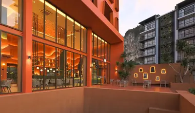 an external view of a building with tables and chairs at Hotel Adam Krabi in Ao Nang Beach
