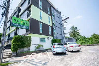 a building with two cars parked in a parking lot at Shyne Place in Phuket Town