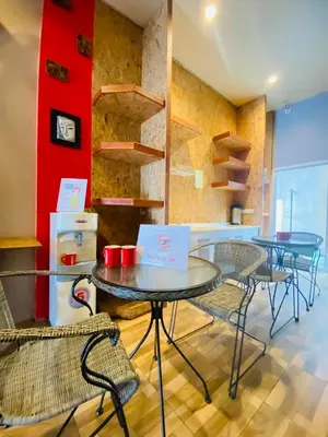 a room with tables and chairs and a red wall at Frutta Hostel in Patong Beach