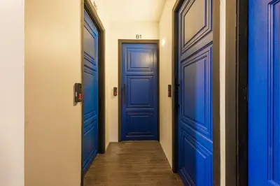 a hallway with two blue doors and a wooden floor at Marco Polo Phuket Poshtel & Bistro in Phuket Town