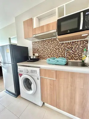 a kitchen with a washing machine and a microwave at Cozy 1 bedroom in prime Bangtao in Bang Tao Beach
