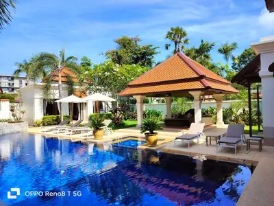 a pool at a resort with chairs and a pavilion at Luxury Sai Taan Villa in Bang Tao in Bang Tao Beach