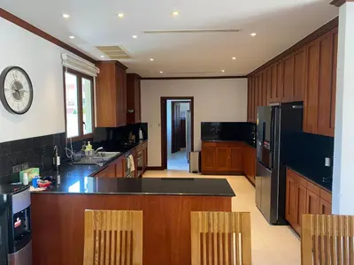 a large kitchen with wooden cabinets and a black refrigerator at Luxury Sai Taan Villa in Bang Tao in Bang Tao Beach