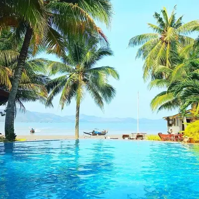 a swimming pool next to a beach with palm trees at Lamsai AC Sea House in Ko Yao Noi