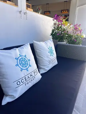 two pillows sitting on top of a bench with flowers at Ocean Pie Phuket - Adult Only in Rawai Beach