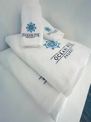 a pile of towels with logos on them at Ocean Pie Phuket - Adult Only in Rawai Beach