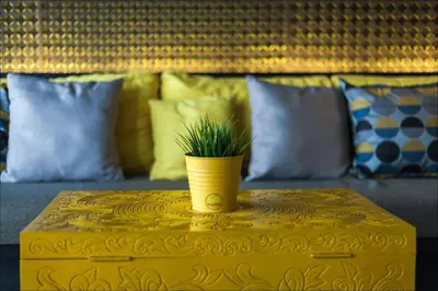 a yellow vase on a table with a plant on it at Fulfill Phuket - SHA in Phuket Town