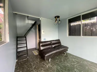 a living room with a leather couch and a staircase at Phi Phi Goodview Bungalow in Phi Phi Don