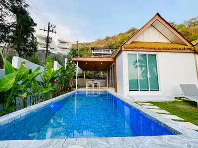 a villa with a swimming pool in front of a house at Baan Saint-Tropez Seaview Villas Kata Beach in Kata Beach