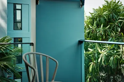 a chair sitting on a balcony with a blue wall at City Gate Kamala D209 by Phuket Sabay Rent in Phuket Town