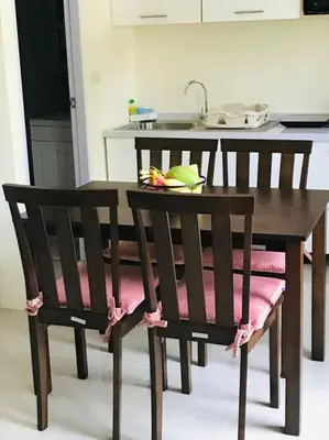 a wooden table with a chair with a plate on it at Summer House,shared pool, private bathroom and kitchen in Ban Phlu Yai