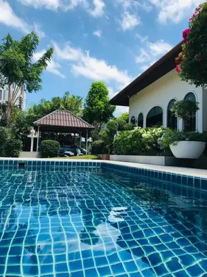 a swimming pool in front of a house at Summer House,shared pool, private bathroom and kitchen in Ban Phlu Yai