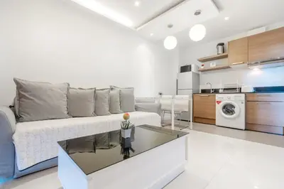 a living room with a couch and a kitchen at The Lago Apartments in Ban Suan