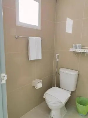a bathroom with a white toilet and a window at Sasimanta in Kamala Beach