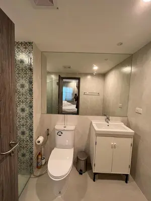 a bathroom with a toilet and a sink and a mirror at 2 Bedrooms Suite Pool Access@The Title Residencies Naiyang in Nai Yang Beach
