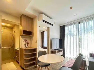 a living room with a table and a room with a tv at Sky park 2 BR lake view in Bang Tao Beach