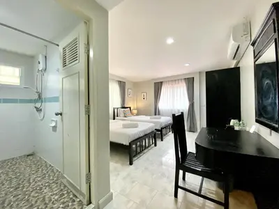 a room with two beds and a bathroom with a piano at Minotel Patong in Patong Beach