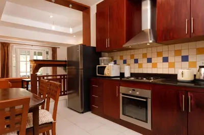 a kitchen with wooden cabinets and a stainless steel refrigerator at Villa with pool, garden and terrace - Kamala #123 in Phuket Town