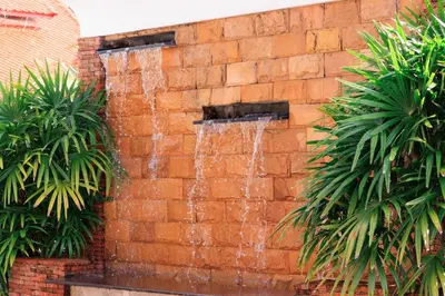 a water fountain on a brick wall with palm trees at Villa with pool, garden and terrace - Kamala #123 in Phuket Town