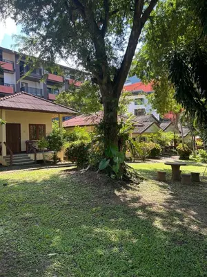 a park with a tree and benches and buildings at Adam Bungalows in Ao Nang Beach