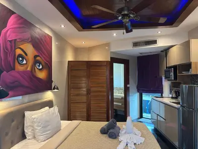 a bedroom with a painting of a woman on the wall at The Club Inn - Kamala Beach in Kamala Beach