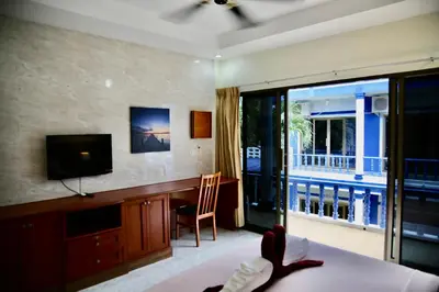 a bedroom with a bed and a television and a balcony at The Club Inn - Kamala Beach in Kamala Beach