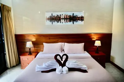 a bed with two towels in the shape of a heart at The Club Inn - Kamala Beach in Kamala Beach