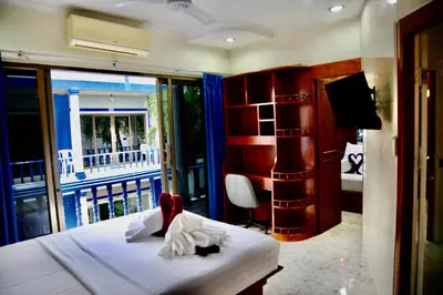 a bedroom with a bed and a balcony with a television at The Club Inn - Kamala Beach in Kamala Beach
