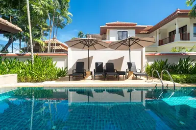 a swimming pool with chairs and an umbrella next to a house at Angsana Villas Laguna-3 Bedroom Pool Villa in Phuket Town
