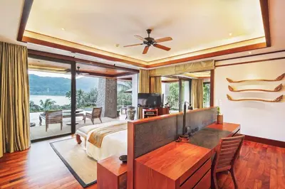 a bedroom with a bed and a desk with a television at Andarada Seaview in Kamala Beach