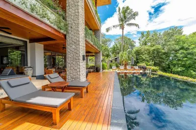 an outdoor deck with chairs and a swimming pool at Andarada Seaview in Kamala Beach