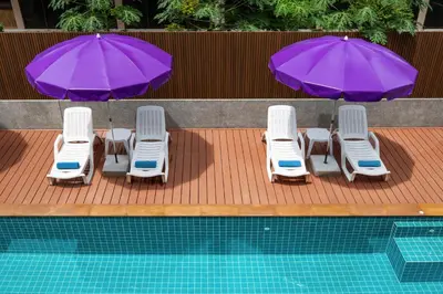 a group of chairs and umbrellas next to a pool at Aspira Resort Klong Muang Krabi in Klong Muang Beach