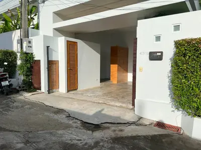 a white building with brown doors and a hedge at Intimate Oasis, 2 bedrooms Pool in Kata Beach
