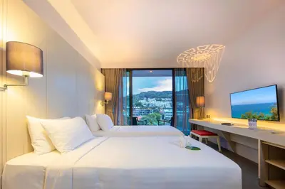 a hotel room with two beds and a desk with a monitor at The Yama Hotel Phuket in Kata Beach