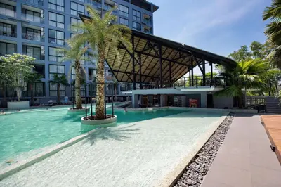 a swimming pool with palm trees in front of a building at Tropics Kamala Hill View Suite CTG P610 near Beach and Fantasea in Kamala Beach
