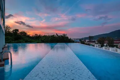 a large swimming pool with a sunset in the background at OCEANA HOME Phuket Kamala in Kamala Beach