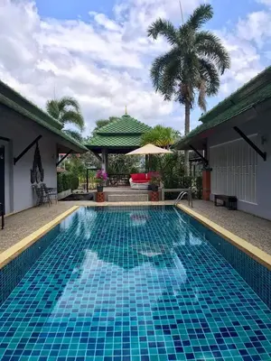a swimming pool with blue tiles on the side of a house at Plumeria Villa Thalang in Ban Pak Lak