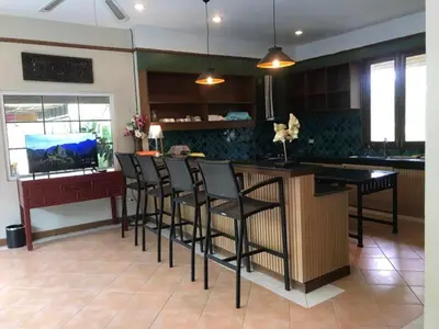 a kitchen with a bar with black chairs in it at Plumeria Villa Thalang in Ban Pak Lak
