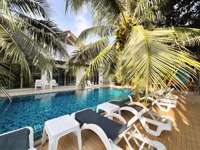 a swimming pool with white chairs and a palm tree at Sierra Hostel in Nai Yang Beach
