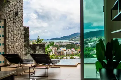 a balcony with chairs and a view of a city at \u82ad\u4e1cVilla2:\u56db\u5367\u6d77\u666f\u522b\u5885 \u53cc\u6d77\u666f \u4e2d\u82f1\u6cf0\u4e09\u6587\u7ba1\u5bb6 in Patong Beach