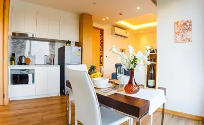 a kitchen and dining room with a table and white chairs at Aristo 2 Apartments by Beringela in Surin Beach