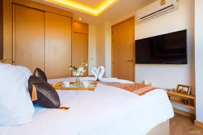 a bedroom with a white bed with a flat screen tv at Aristo 2 Apartments by Beringela in Surin Beach