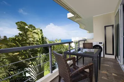 a balcony with a table and chairs and the ocean at Woodbridge Property at Karon Butterfly in Karon Beach