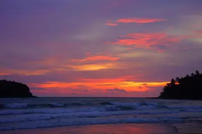 a sunset on a beach with the ocean at Kana Hotel Phuket\u666e\u5409\u5c9b\u5361\u5a1c\u9152\u5e97 in Rawai Beach