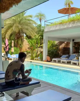 a man sitting on a bench next to a swimming pool at Kana Hotel Phuket\u666e\u5409\u5c9b\u5361\u5a1c\u9152\u5e97 in Rawai Beach