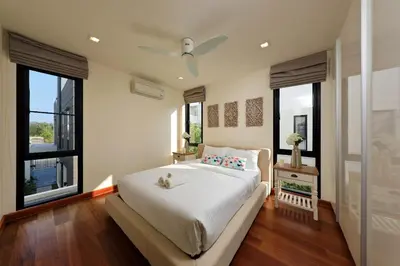 a bedroom with a bed with white sheets and windows at Laguna Park Grand Villa na Bang Tao in Phuket Town