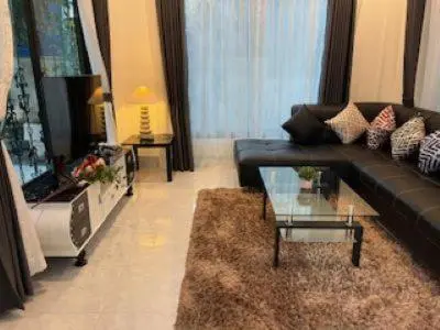 a living room with a black couch and a glass table at Kata Sea Blue Villa in Kata Beach