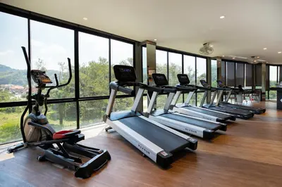 a row of cardio machines in a gym with windows at tropics Kamala CTG L604, near FantaSea & Café Del Mar Beach Club in Kamala Beach