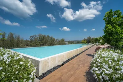 a large swimming pool with a brick wall and flowers at SkyPark Bangtao, Laguna 2 bedroom apartment 5 minutes from the beach in Phuket Town