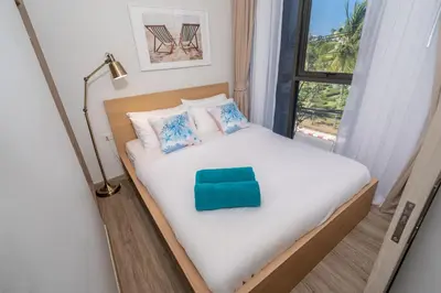 a bedroom with a bed with a green pillow on it at SkyPark Bangtao, Laguna 2 bedroom apartment 5 minutes from the beach in Phuket Town